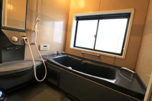 a bathroom with a bath tub and a window at ウインザー宇佐美 in Ito