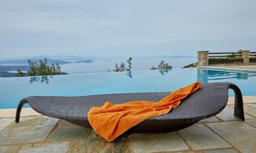 an orange blanket sitting on a chair next to a pool at Black Diamond Luxury Unique Villa Pelion in Lafkos