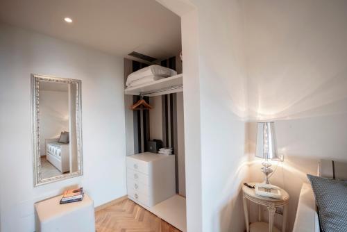 a white bedroom with a bed and a mirror at Hotel Bellevue in Gardone Riviera