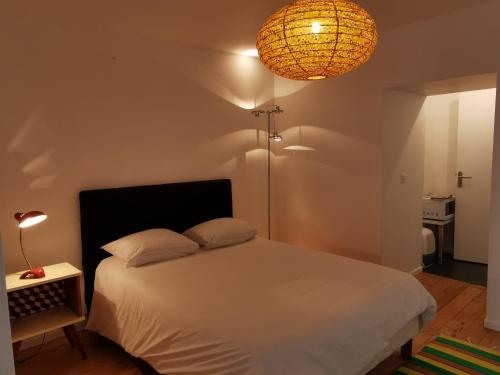 Un dormitorio con una cama blanca y una lámpara. en l'Otis et le Titouan Saint-Sauveur, en Dinan