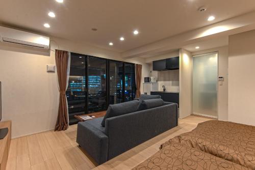 ein Schlafzimmer mit einem Bett und einem Sofa sowie eine Küche in der Unterkunft MK Hotels Nishinakasu in Fukuoka