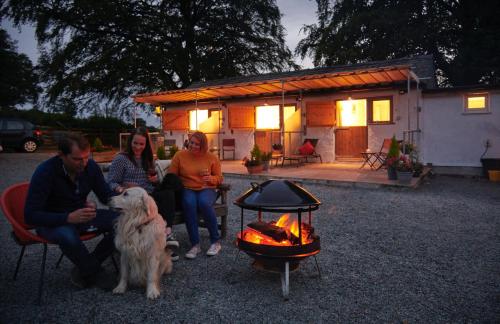 Un grupo de personas y un perro sentados junto al fuego en Newlands Farm Stables en Kendal