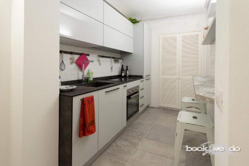 une cuisine avec des placards blancs et un comptoir noir dans l'établissement La Rocca 2 - Bookwedo, à Porto Ercole