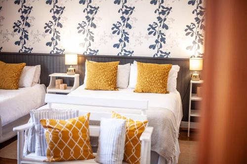 1 dormitorio con 2 camas y almohadas amarillas y blancas en Flametree Guesthouse, en Swellendam