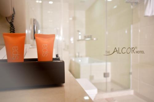 two orange cups sitting on a counter in a bathroom at The Alcor Hotel in Jamshedpur