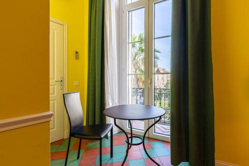 une table et deux chaises dans une pièce avec une fenêtre dans l'établissement Cannes-Hyper-Centre, à Cannes