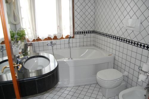 a bathroom with a tub and a toilet and a sink at Hotel Olympic in Saint Vincent