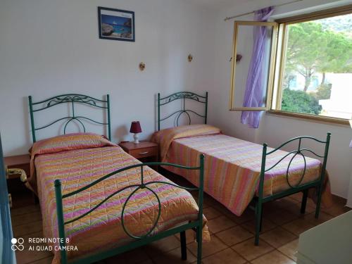 2 camas individuales en una habitación con ventana en Appartamenti Manuela, en Cala Gonone