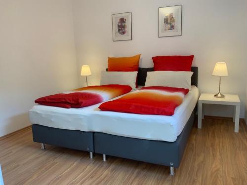 1 dormitorio con 2 camas con almohadas de color rojo y naranja en Helle FEWO, 60 qm, Souterrain, eigener Eingang, Rhein und Nahe, en Bingen am Rhein