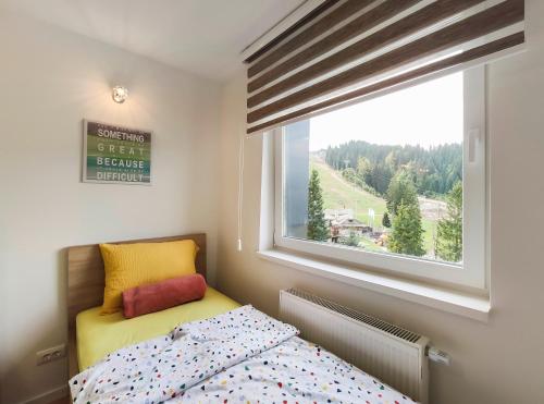 um pequeno quarto com uma cama e uma janela em Apartmani Jahorina Olimpijska kuca em Jahorina