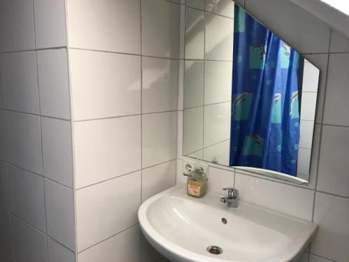 a white bathroom with a sink and a mirror at Pension Alis Augsburg in Augsburg