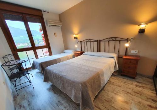 a bedroom with two beds and a large window at Los Acebos Arriondas in Arriondas