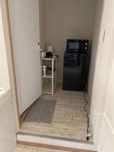 a hallway with a black refrigerator and a microwave at ロワジール岩槻301 in Iwatsuki