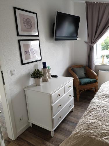 ein Schlafzimmer mit einer weißen Kommode und einem Fernseher an der Wand in der Unterkunft Ferienwohnung Muschelsucher in Juliusruh