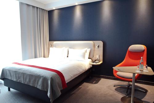 a hotel room with a bed and a red chair at Holiday Inn Express Oberhausen by IHG in Oberhausen
