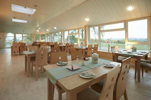 um restaurante com mesas e cadeiras de madeira e janelas em Hotel Weimarer Berg em Apolda