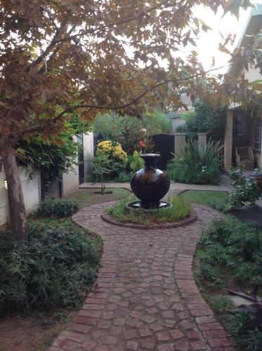a garden with a large vase on a walkway at Schilbach House in Parys