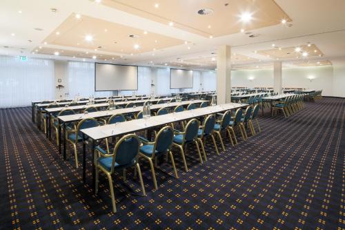 a conference room with tables and chairs and a screen at H+ Hotel Köln Hürth in Hürth
