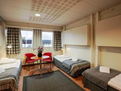 Cette chambre d'hôtel comprend deux lits, une table et des chaises. dans l'établissement Hotel Tikkurila, à Vantaa