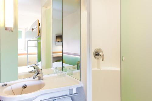 bagno con lavandino e specchio di ibis budget Birmingham International Airport – NEC a Bickenhill