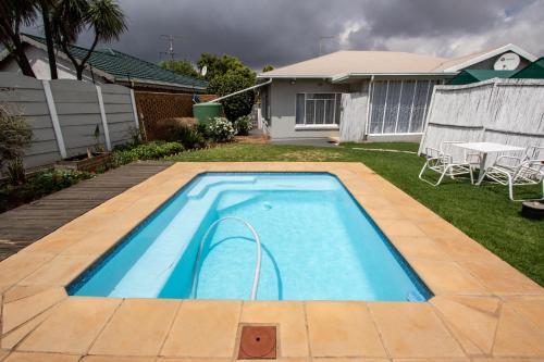 a swimming pool in the yard of a house at WILLOW GUEST HOUSE in Boksburg
