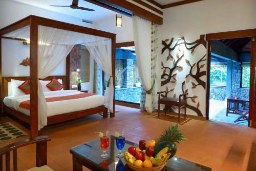 a bedroom with a bed and a table with a bowl of fruit at Vythiri Resort in Vythiri