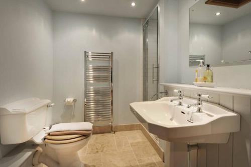 a white bathroom with a toilet and a sink at Old Oak Barn - Beautiful barn conversion with wonderful Jacuzzi hot tub in Stowmarket