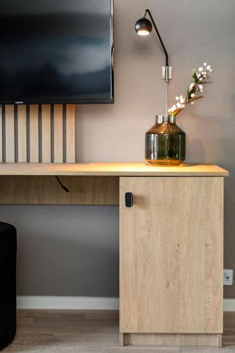 a desk with a lamp and a vase with flowers on it at BJØRVIKA APARTMENTS, Teaterplassen, Oslo city center in Oslo