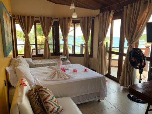 ein Schlafzimmer mit einem weißen Bett mit Blick auf das Meer in der Unterkunft Guesthouse Saint Tropez in Arraial do Cabo