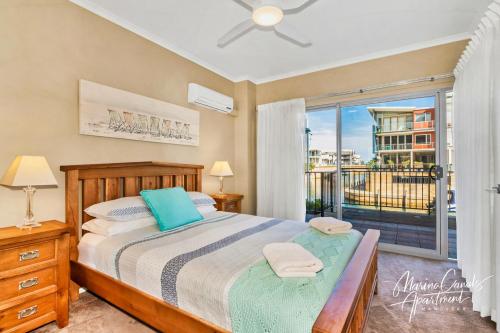a bedroom with a bed and a balcony at Marina Canals Apartment in Mandurah