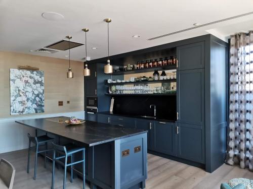 a kitchen with a blue island with a bar at Charles Hope Canary Wharf South Quay in London