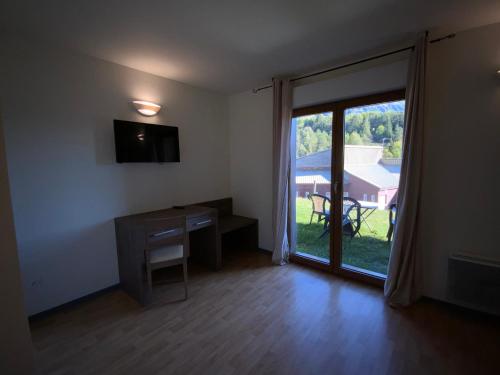 a room with a desk and a sliding glass door at L'Inattendu in Le Vernet