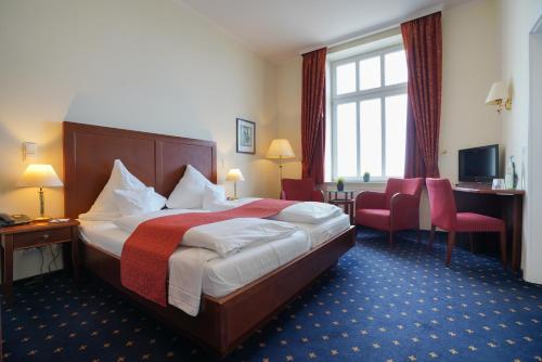 a hotel room with a bed and a desk at Strandhotel Ostfriesenhof in Borkum