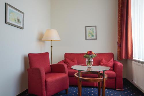 a living room with two red chairs and a table at Strandhotel Ostfriesenhof in Borkum