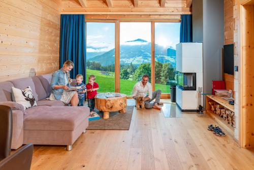 a family sitting in a living room with a large window at Rittis Alpin Chalets Dachstein in Ramsau am Dachstein