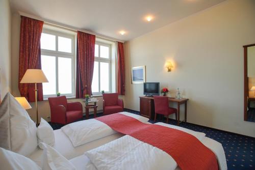 a hotel room with a large bed and chairs at Strandhotel Ostfriesenhof in Borkum