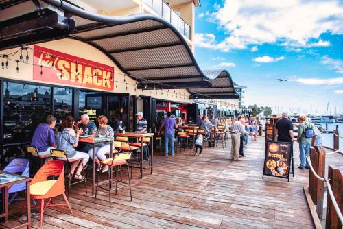 a group of people sitting at tables on a boardwalk at Marina Canals Apartment in Mandurah