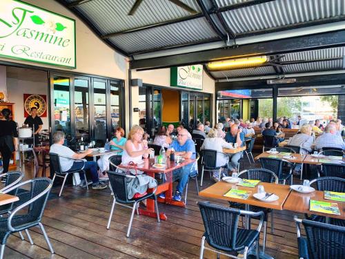 a group of people sitting at tables in a restaurant at Marina Canals Apartment in Mandurah