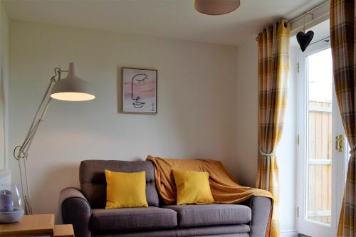 a living room with a couch with yellow pillows at Woodlands View in Halesworth