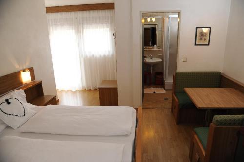 a hotel room with a bed and a table and a sink at Hotel Sole Family Hotel in Predazzo