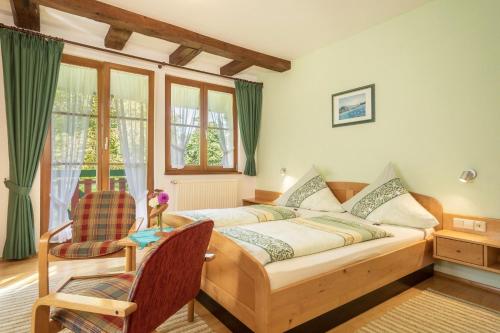a bedroom with a bed and a chair and windows at Ferienwohnung Risthof 2 in Owingen