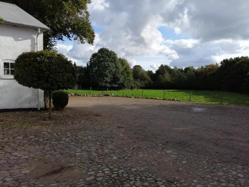 a gravel driveway in front of a white building at Pension Slotsgaarden jels in Jels