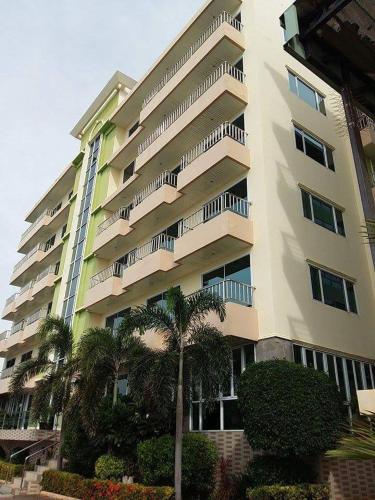 a tall building with palm trees in front of it at โรงแรม ชาโตว์วิสต้า in Chon Buri