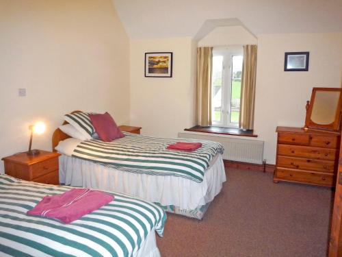 a bedroom with two beds and a dresser and a window at Stone Cottage Kenmare by Trident Holiday Homes in Kenmare