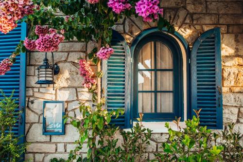 Büyükada Loc'ada في جزر الأمراء: نافذة بها مصاريع زرقاء على مبنى حجري به زهور