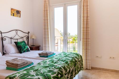 a bedroom with a bed with a green and white blanket at Casa la Rosaleda in Muchamiel