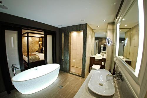 a bathroom with a large white tub and a sink at Grosvenor Pulford Hotel & Spa in Pulford