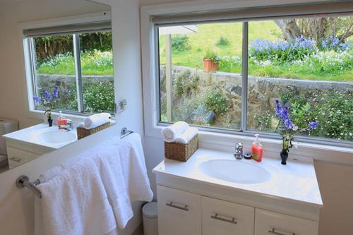 a bathroom with two sinks and a window at Sea Salt House in Stanley