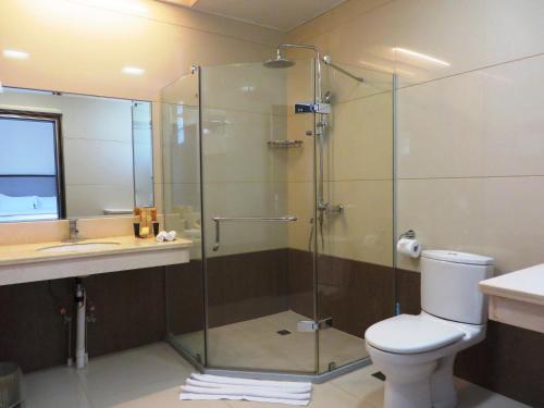 a bathroom with a shower and a toilet and a sink at Plaza Hotel in Dili