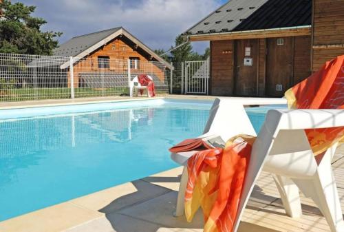 une piscine avec deux chaises et une maison dans l'établissement Residence La Crete du Berger - maeva Home, à La Joue du Loup